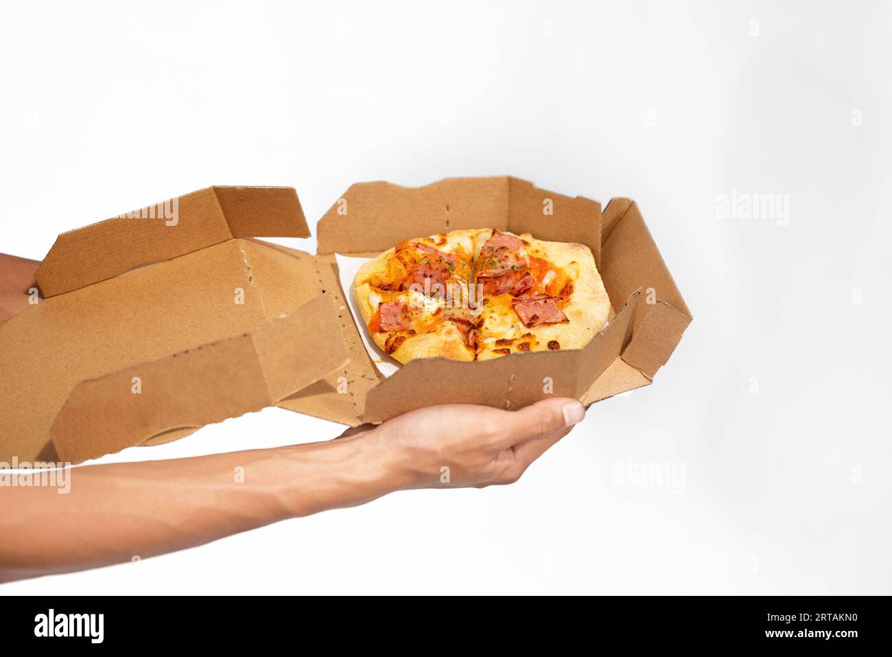 Una mano umana che tiene la pizza su una scatola di cartone con uno sfondo bianco Foto Stock