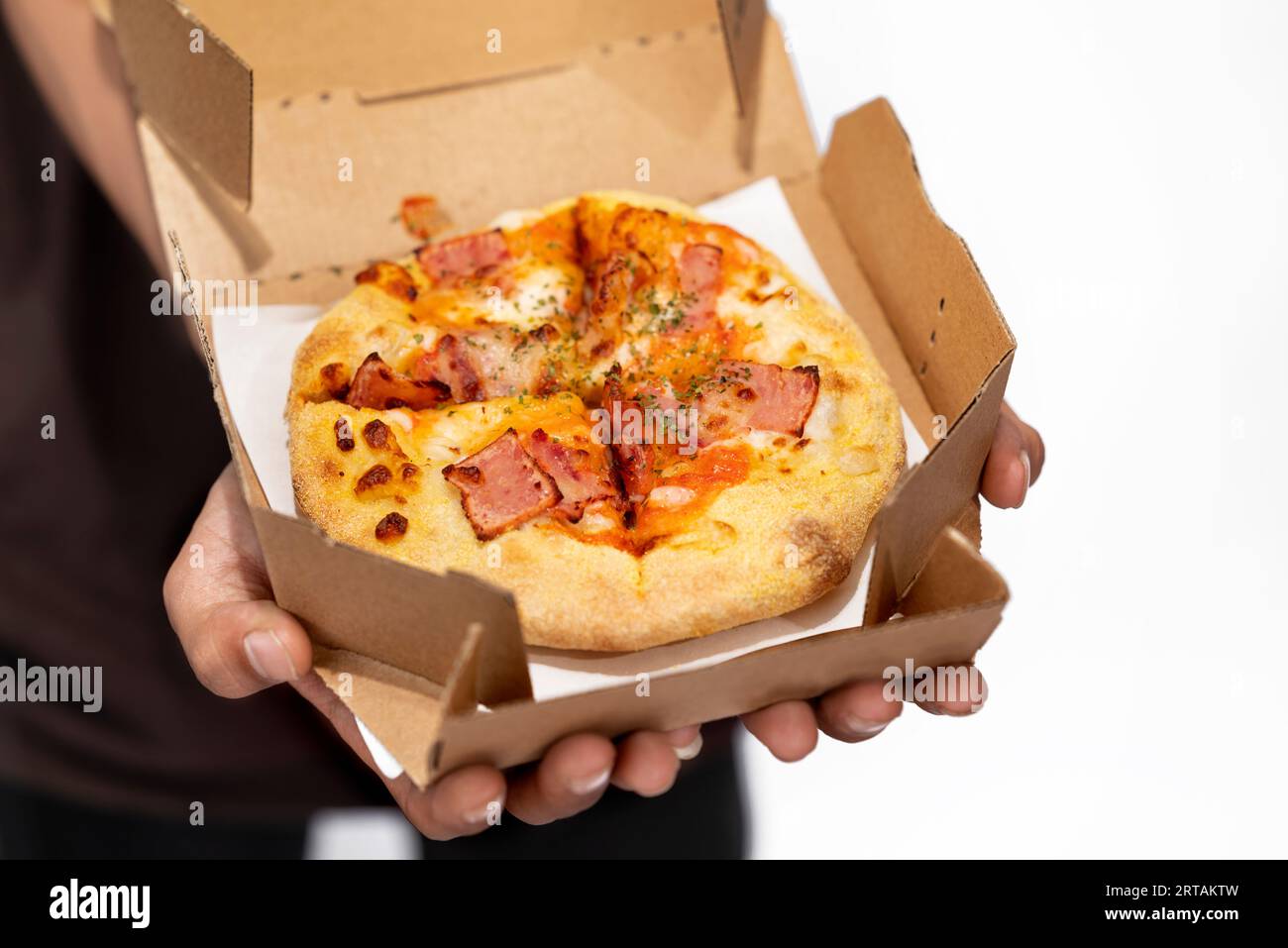 Una mano umana che tiene la pizza su una scatola di cartone con uno sfondo bianco Foto Stock