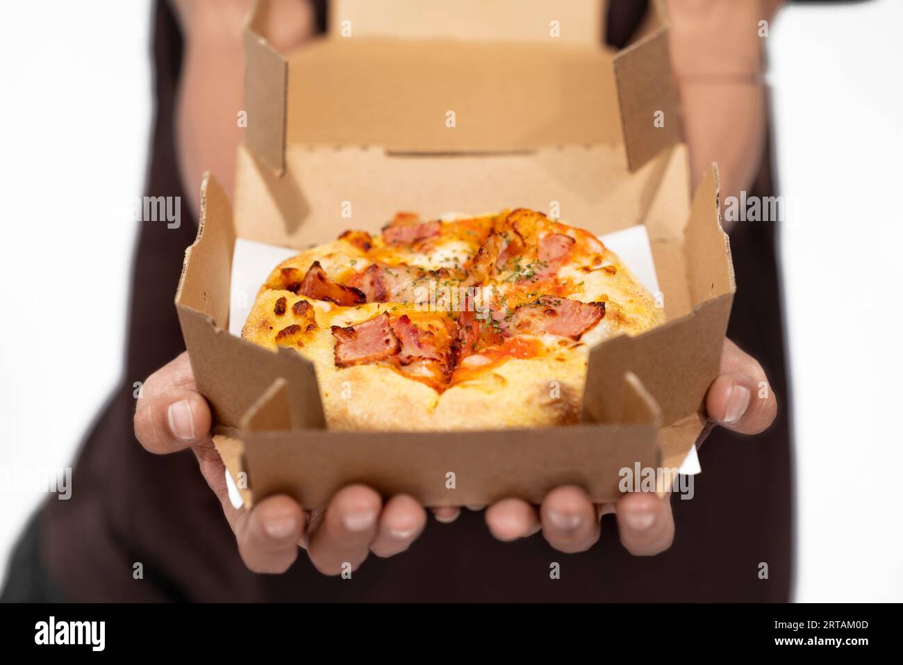 Una mano umana che tiene la pizza su una scatola di cartone con uno sfondo bianco Foto Stock