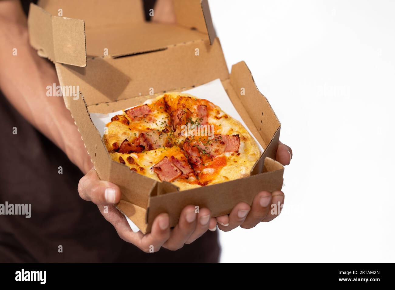 Una mano umana che tiene la pizza su una scatola di cartone con uno sfondo bianco Foto Stock