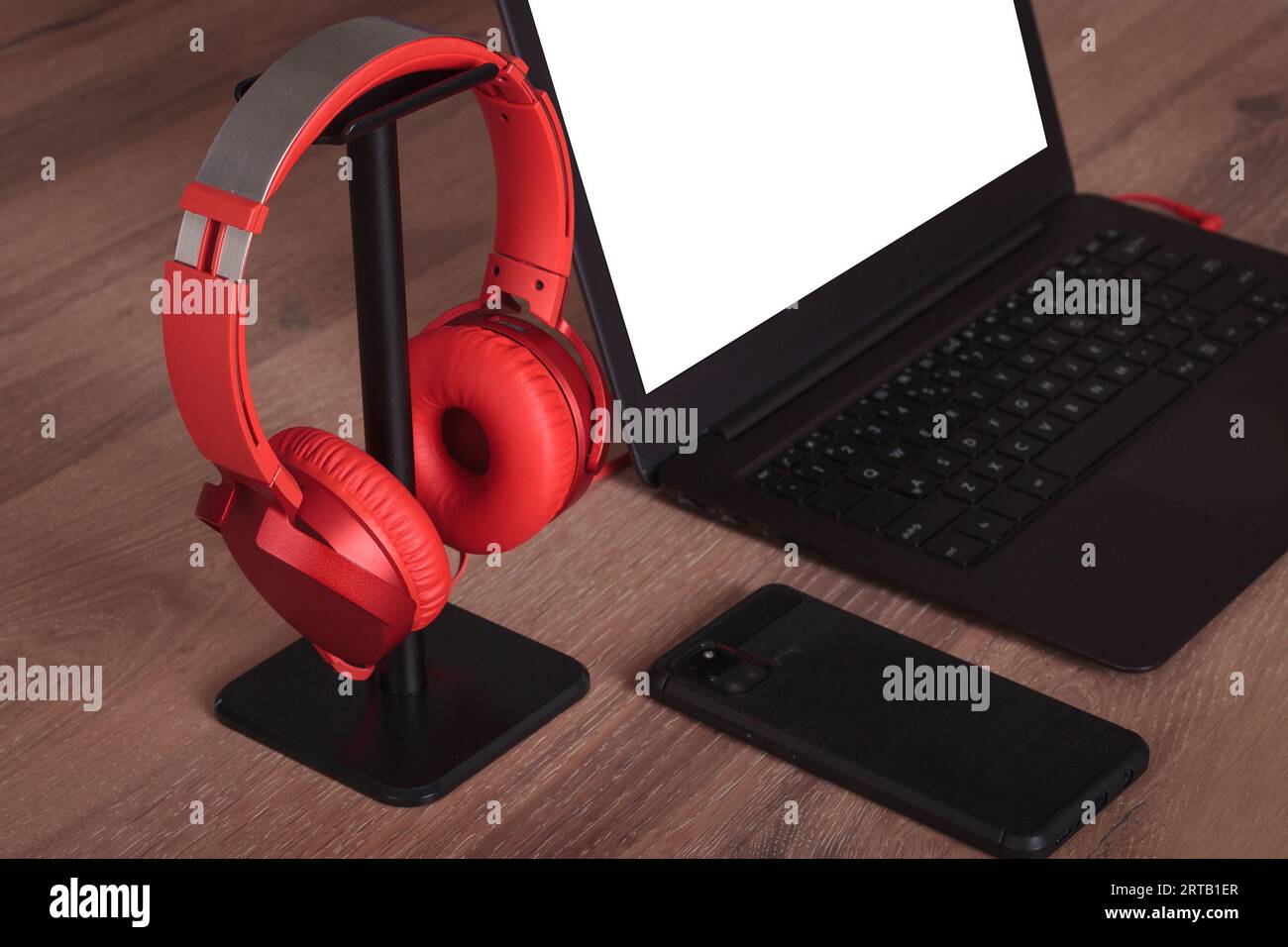 Configurazione dell'area di lavoro: Portatile e cuffie rosse sulla scrivania Foto Stock