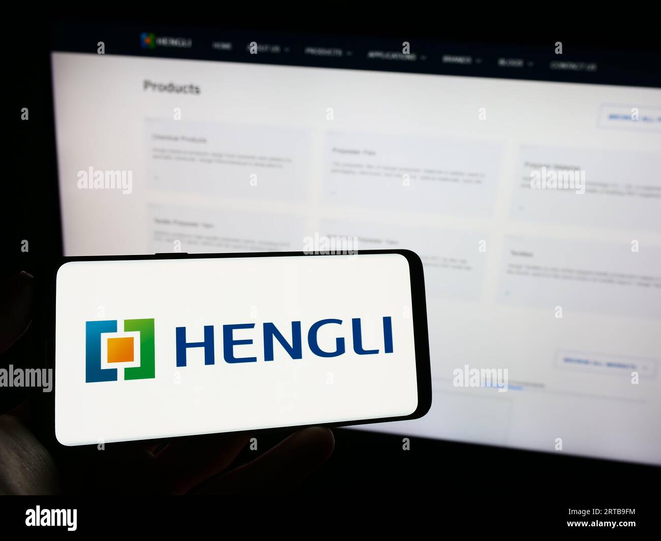 Persona che possiede un telefono cellulare con il logo della società petrolchimica cinese Hengli Group sullo schermo davanti alla pagina Web. Concentrarsi sul display del telefono. Foto Stock