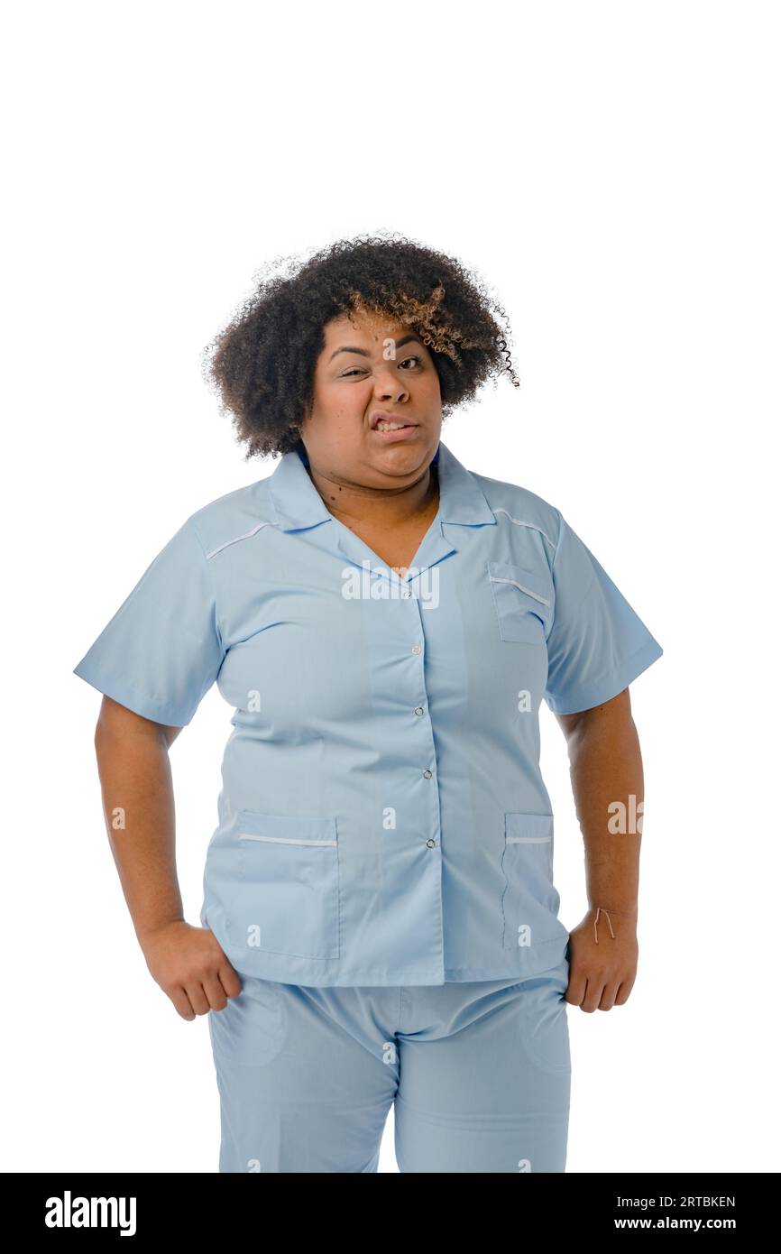 Ritratto verticale della giovane donna latina afro di etnia venezuelana, con uniforme blu, infermiera in piedi che schiaccia la macchina fotografica in disgusto e guarda Foto Stock
