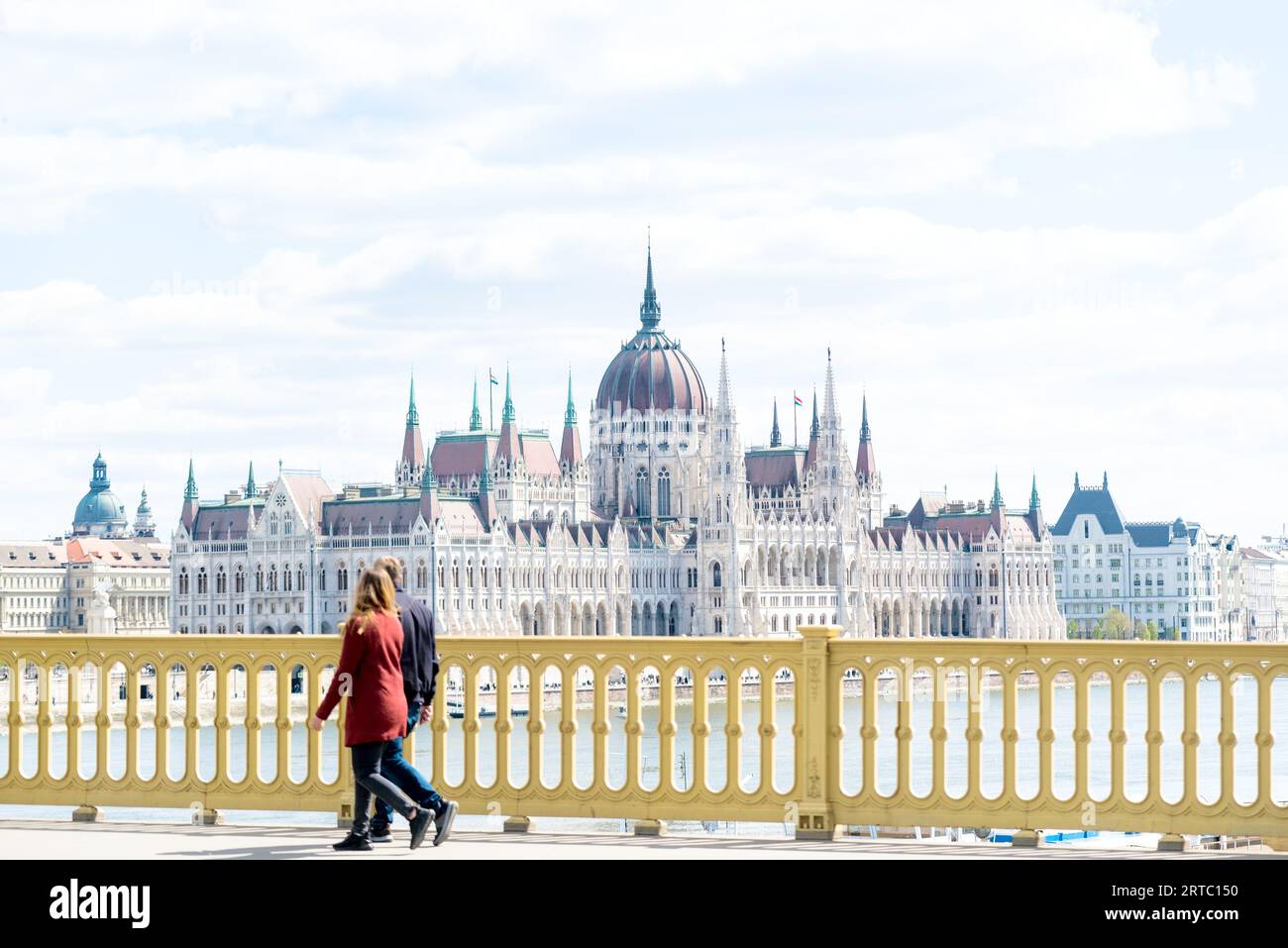 Coppia che attraversa il ponte Margit contro il Parlamento ungherese Foto Stock