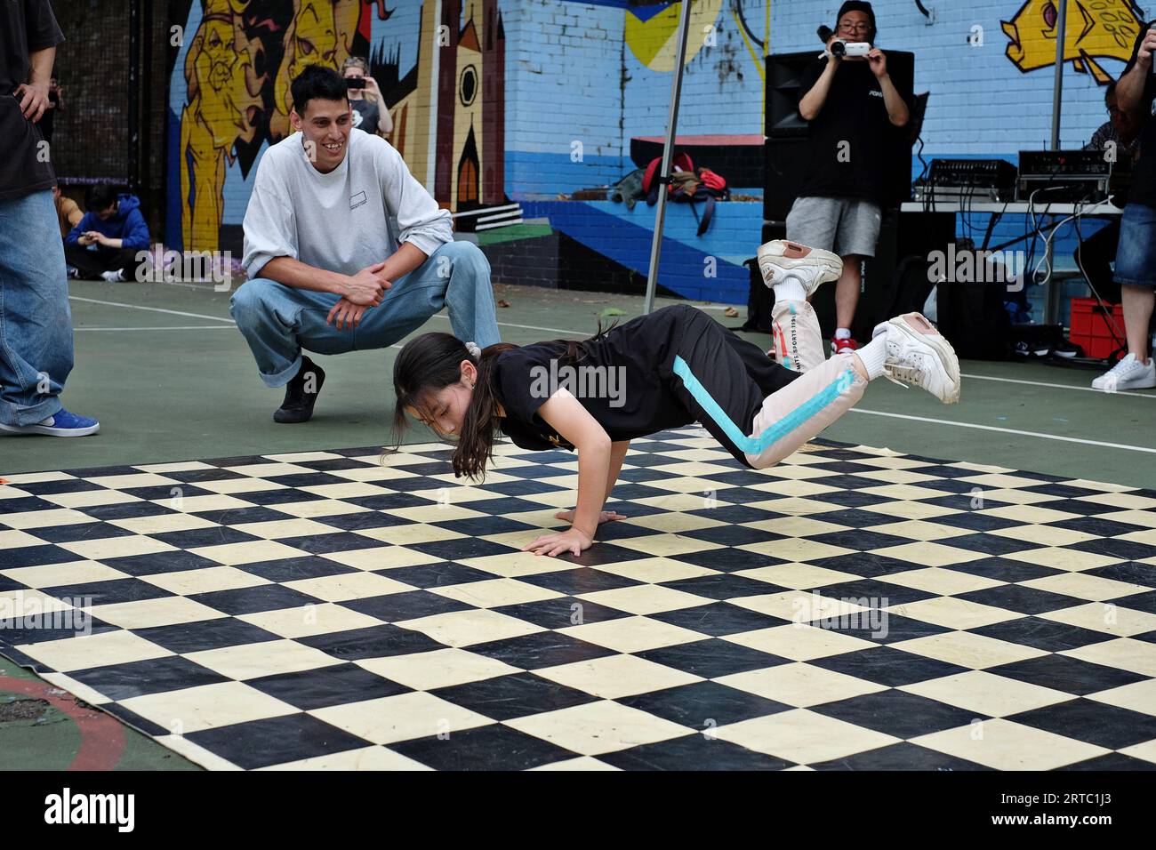 Una giovane ballerina Bgirl esegue una breakdance Freeze con performance e battaglie di competizione sui campi da basket di Woolloomooloo, Sydney Foto Stock
