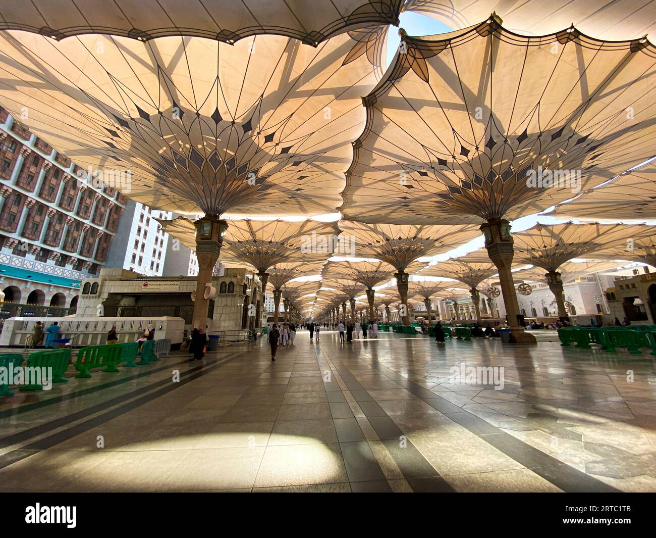 Medina, Arabia Saudita - 22 agosto 2023: I pellegrini camminano sotto ombrelli giganti nel complesso della Moschea Nabawi. Baldacchino a Masjid Nabawi a Medina, in Arabia Saudita Foto Stock