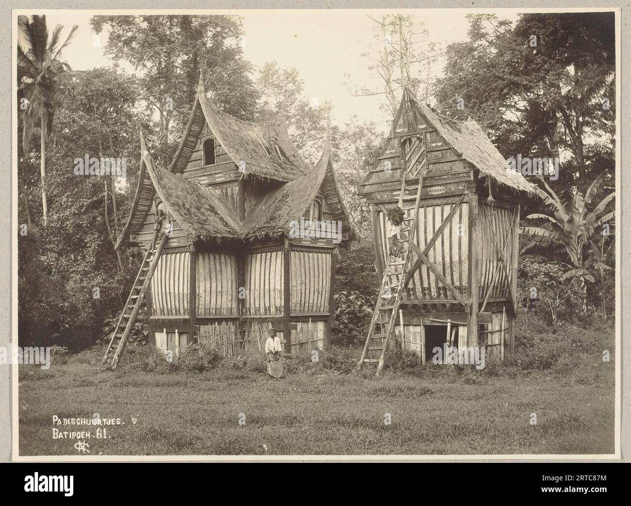 Sumatra occidentale, Indonesia, 1900, foto d'archivio vintage, due case di Minangkabau dove viene immagazzinato il riso. La parte superiore è decorata con intagli in legno e presenta porte accessibili da una scala. Foto Stock