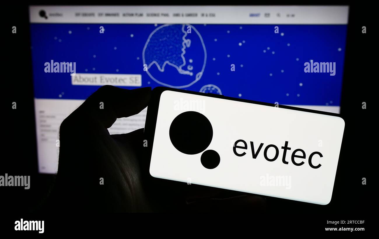 Persona che detiene lo smartphone con il logo della società tedesca di ricerca di farmaci Evotec se sullo schermo davanti al sito Web. Concentrarsi sul display del telefono. Foto Stock