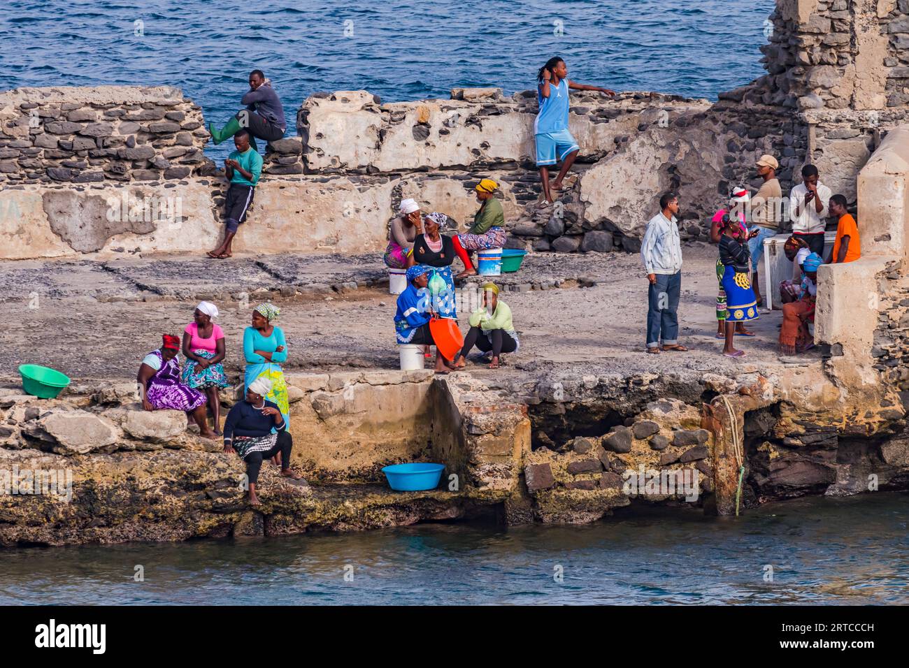 Donne e uomini attendono l'arrivo di un peschereccio al porto improvvisato, le isole di Capo Verde Foto Stock