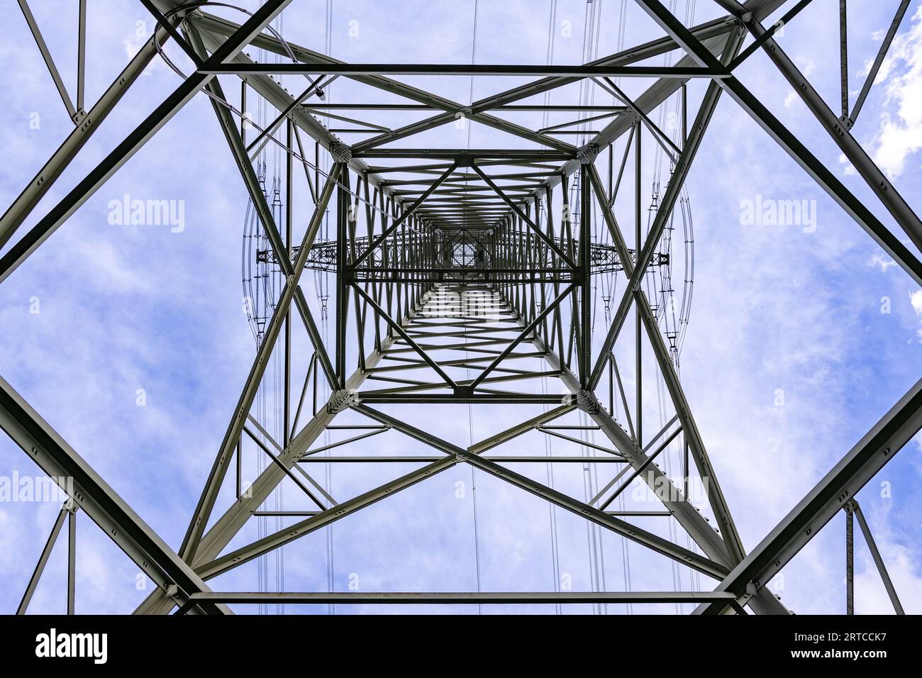 Struttura in acciaio per palo elettrico con molte linee elettriche per il trasporto di elettricità fotografata direttamente da sotto contro il cielo Foto Stock