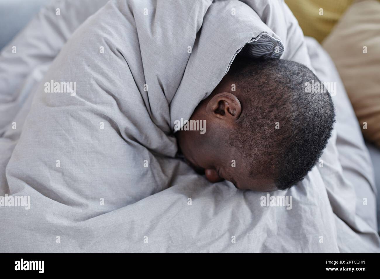 Ritratto minimo di uomo nero depresso avvolto in coperta che lotta con problemi di salute mentale Foto Stock