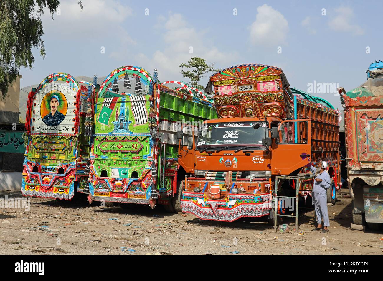 Camion pakistani parcheggiati fuori da un negozio di verniciatura vicino a Islamabad Foto Stock