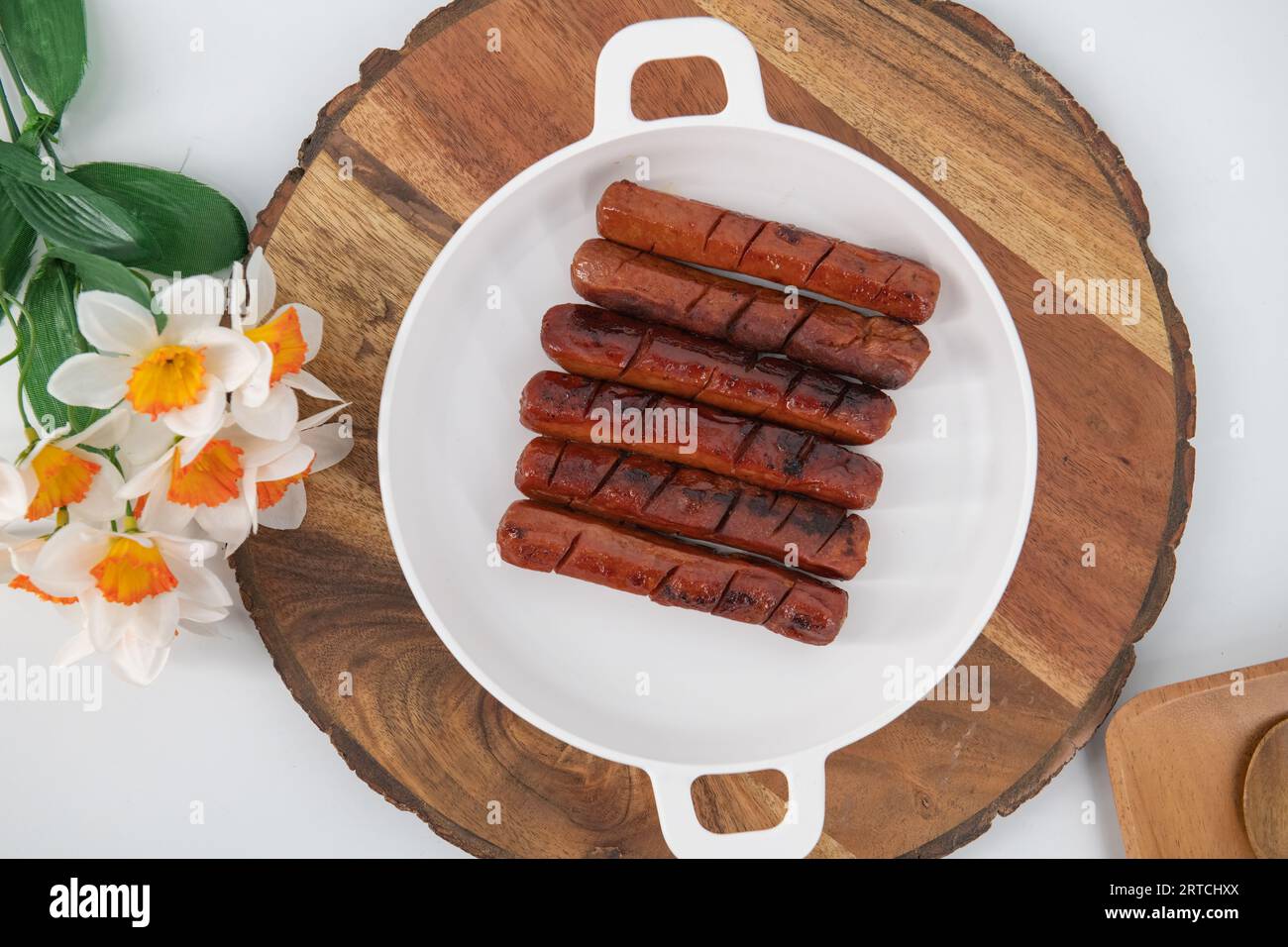 Vista dall'alto delle salsicce fritte e grigliate con salsa in un piatto bianco e fondo isolato. Salsicce di pollo speziate fritte nell'olio. Foto Stock