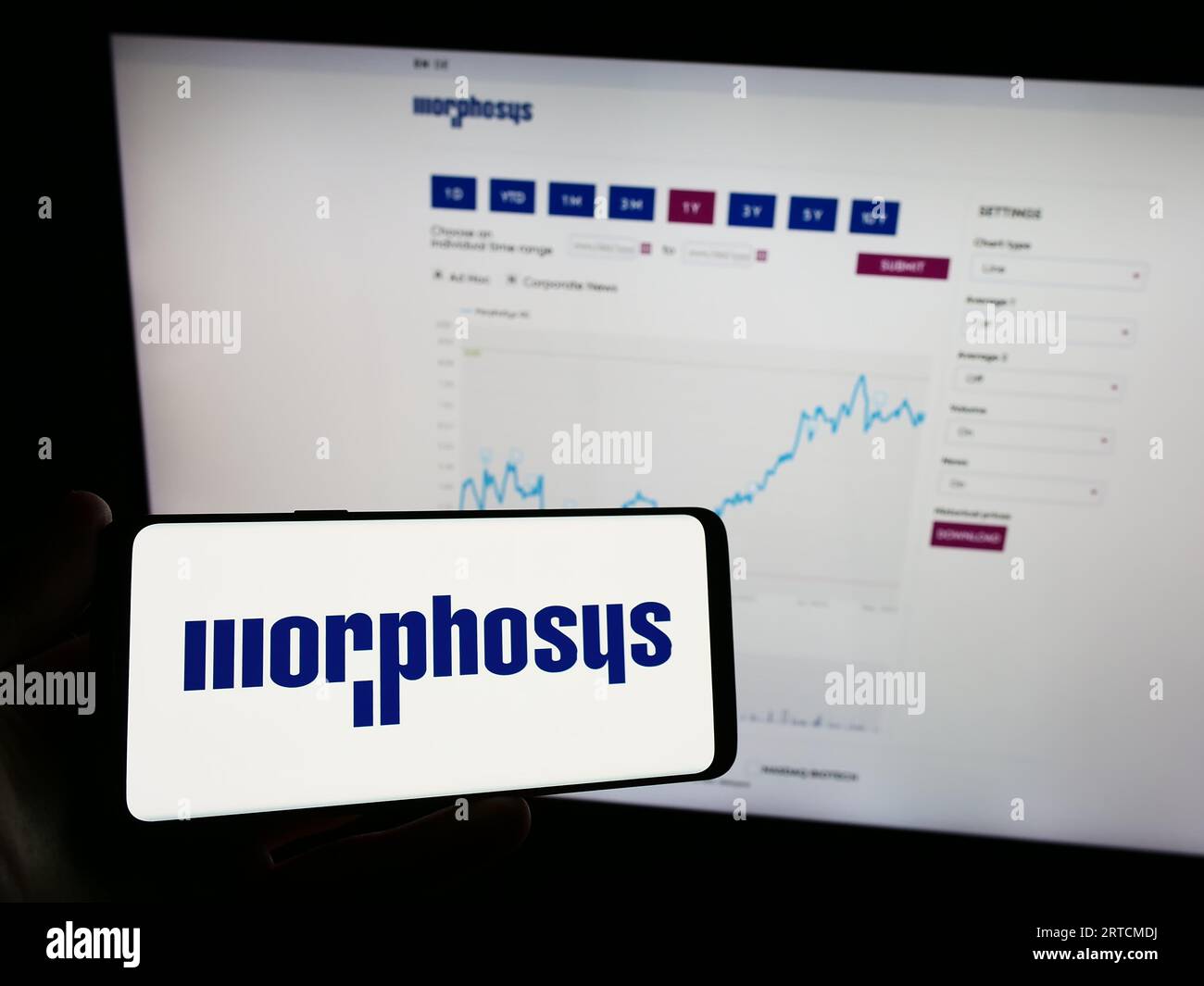 Persona che possiede un telefono cellulare con il logo dell'azienda biofarmaceutica tedesca MorphoSys AG sullo schermo davanti alla pagina Web. Concentrarsi sul display del telefono. Foto Stock