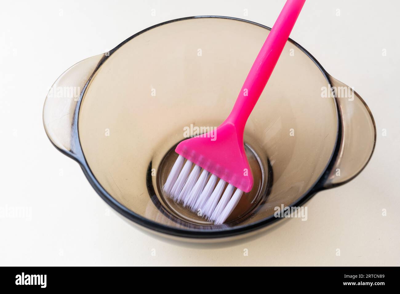 ragazza con guanti protettivi in gomma blu che tiene una spazzola tra le mani e mescola la tintura per capelli primo piano cura dei capelli a casa. Foto Stock