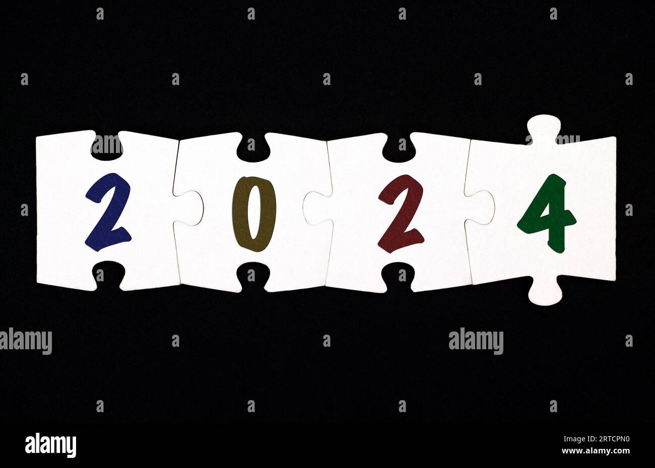 Quattro pezzi del puzzle con i numeri 2 0 2 4 sono collegati tra loro su uno sfondo nero Foto Stock