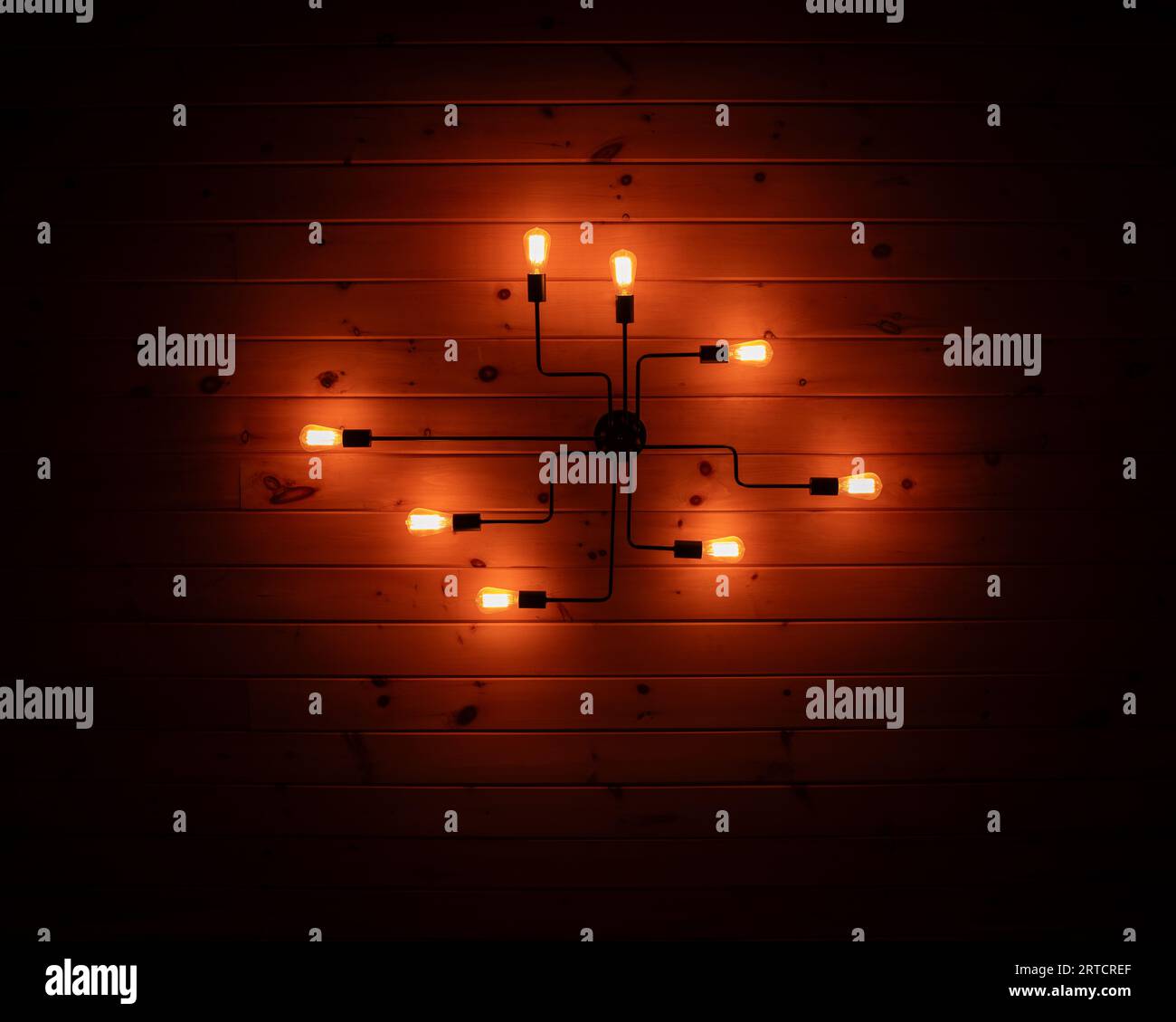 Esclusivo apparecchio di illuminazione montato su una parete di legno. Luci sul soffitto di notte. Foto Stock