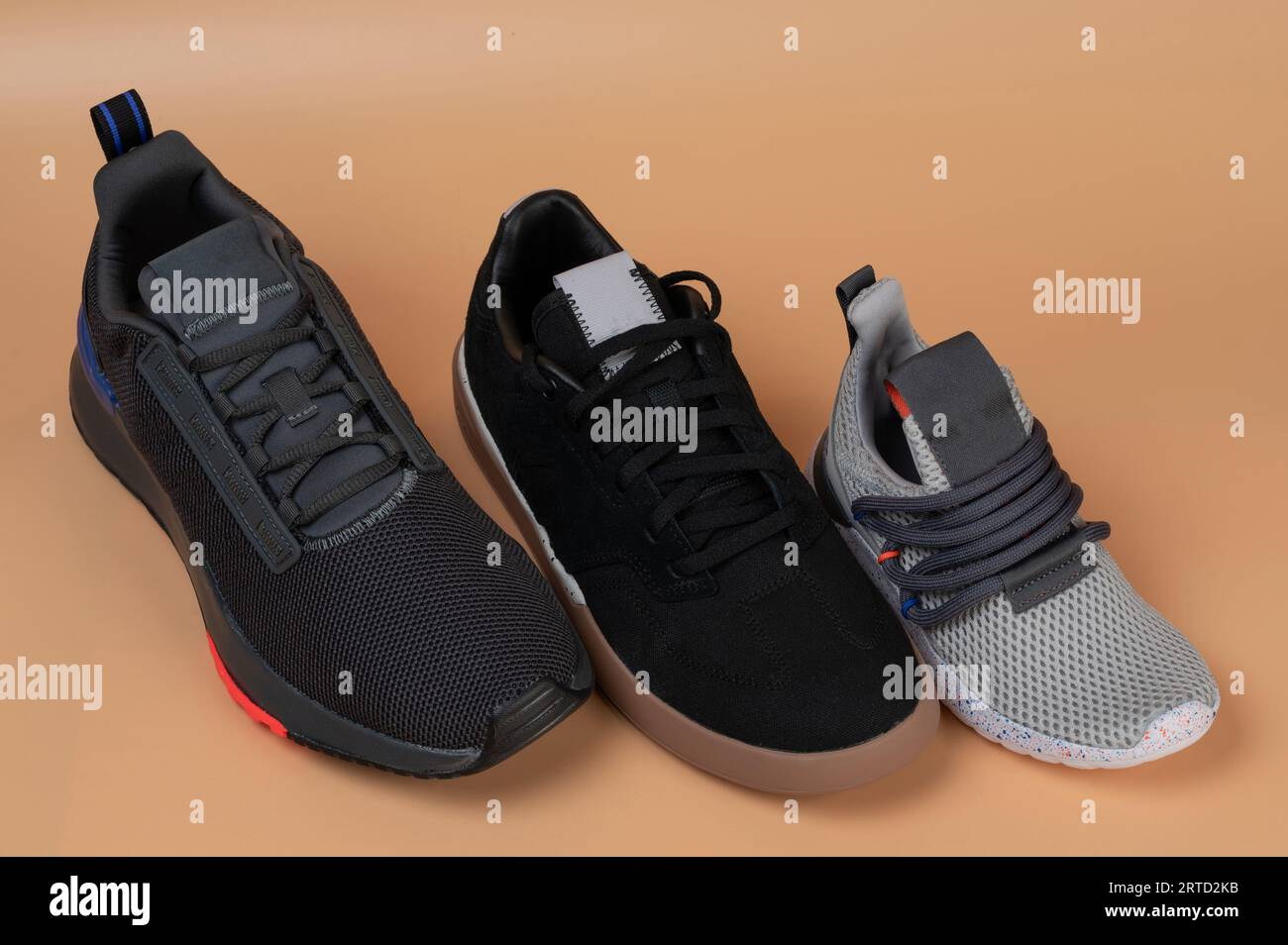 Linea di scarpe sportive di dimensioni diverse su sfondo marrone isolato Foto Stock