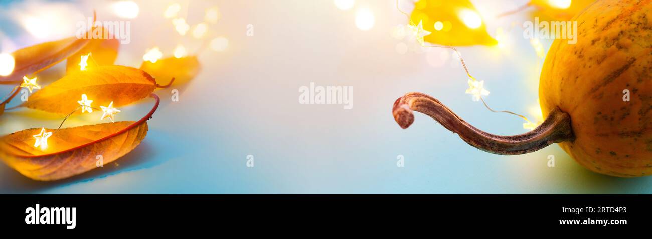 Zucche autunnali e foglie autunnali gialle su sfondo azzurro come decorazioni per il giorno del Ringraziamento; banner del Ringraziamento con spazio copia; Foto Stock