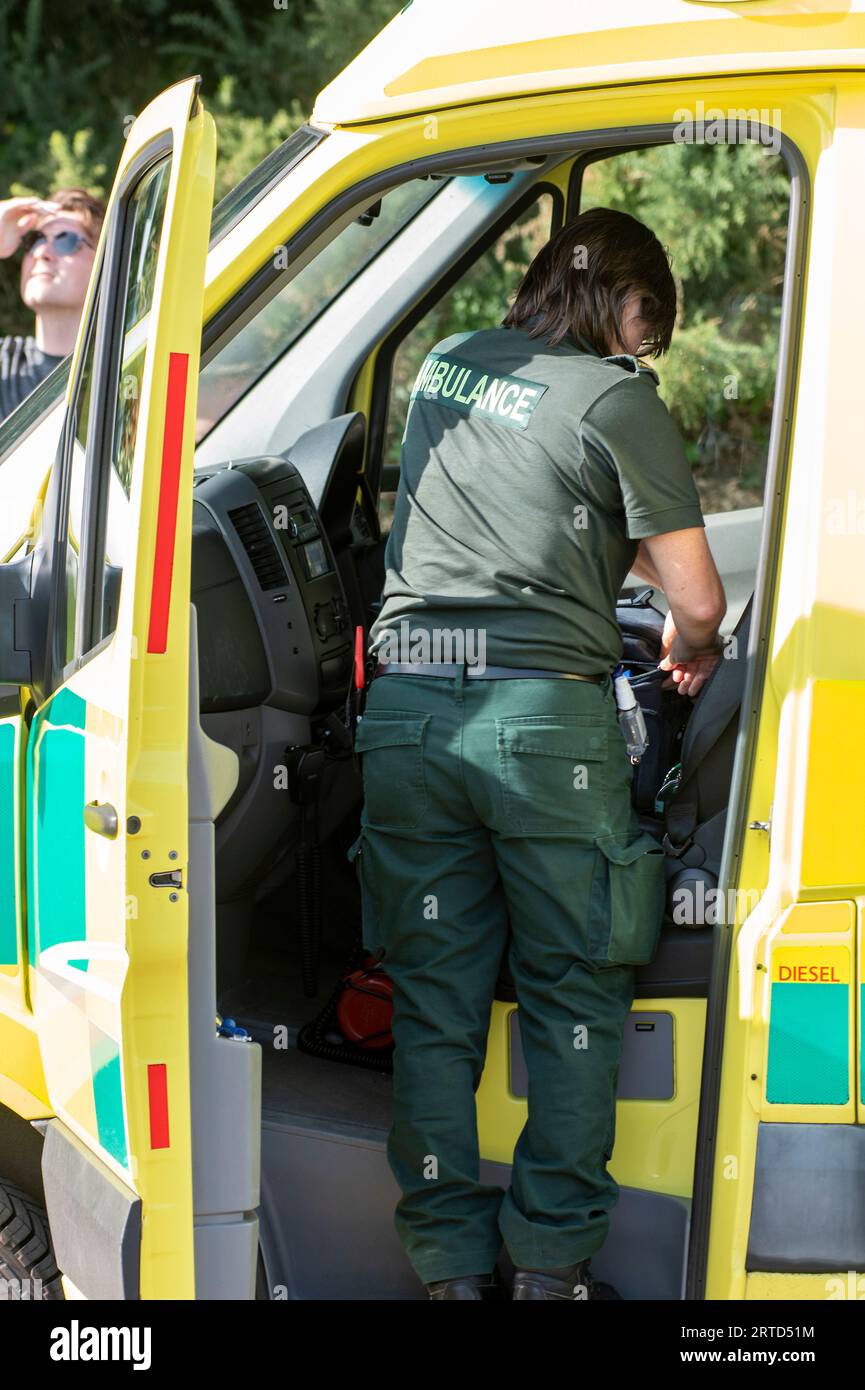 ambulanza paramedico o tecnico che recupera il kit di emergenza dal bordo di un veicolo ambulanza in prima linea. Foto Stock