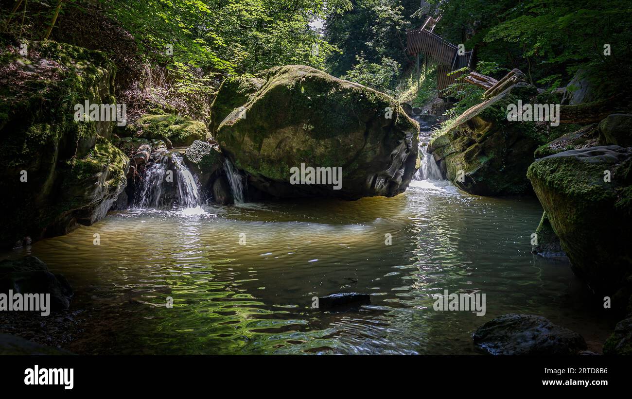 Acqua che cade e una piccola cascata tra le rocce solide nella foresta di Mullerthal, un ambiente da favola in Lussemburgo Foto Stock
