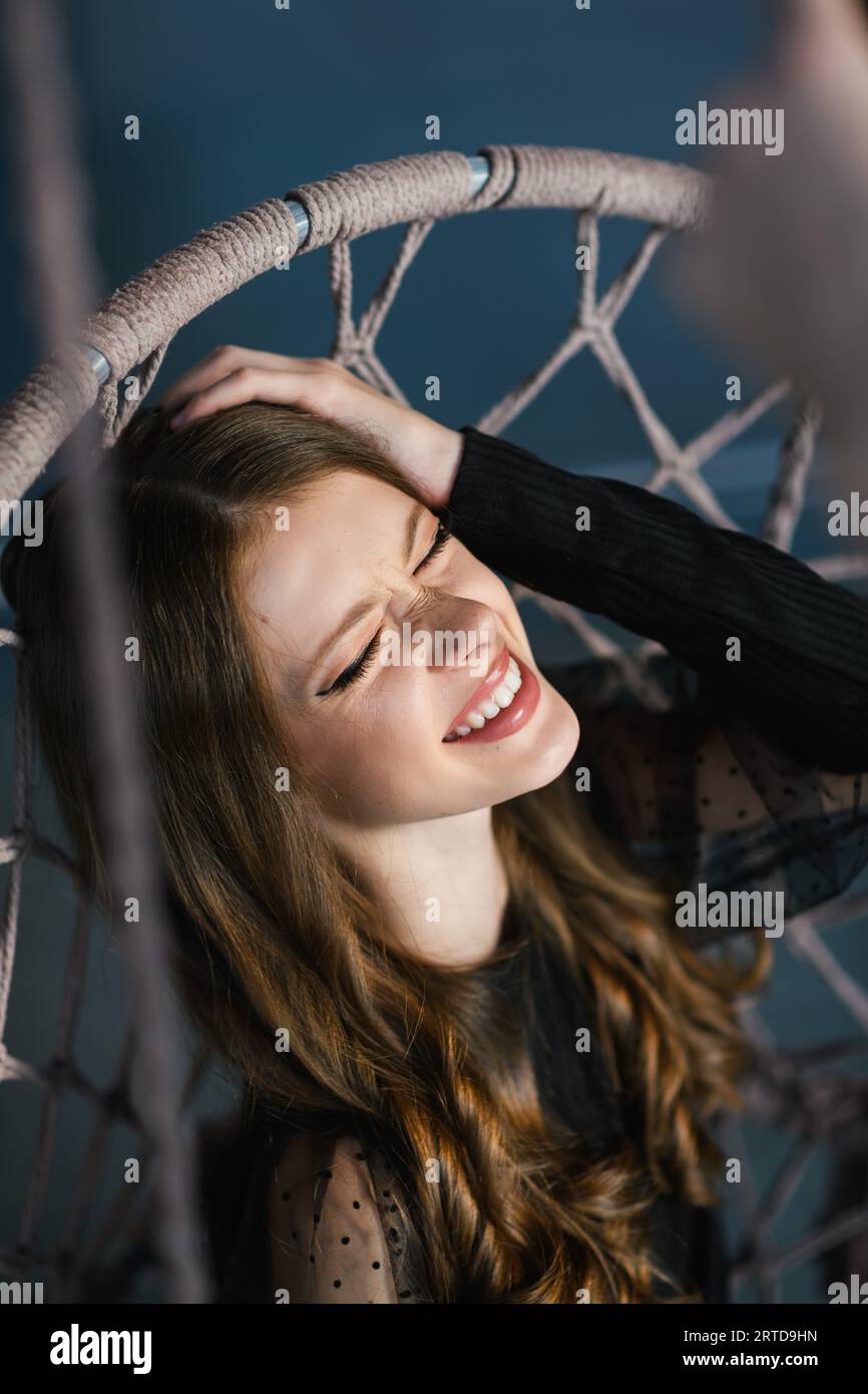 Ritratto di una ragazza adolescente con i capelli ricci. La ragazza sorride tenendo gli occhi chiusi. Vista dall'alto. Foto Stock