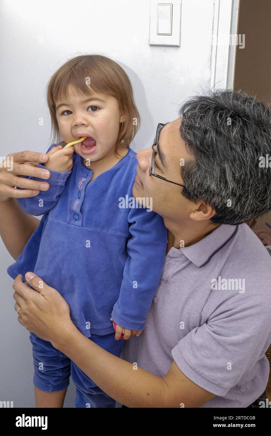 Papà aiuta sua figlia a lavarsi i denti. Foto Stock