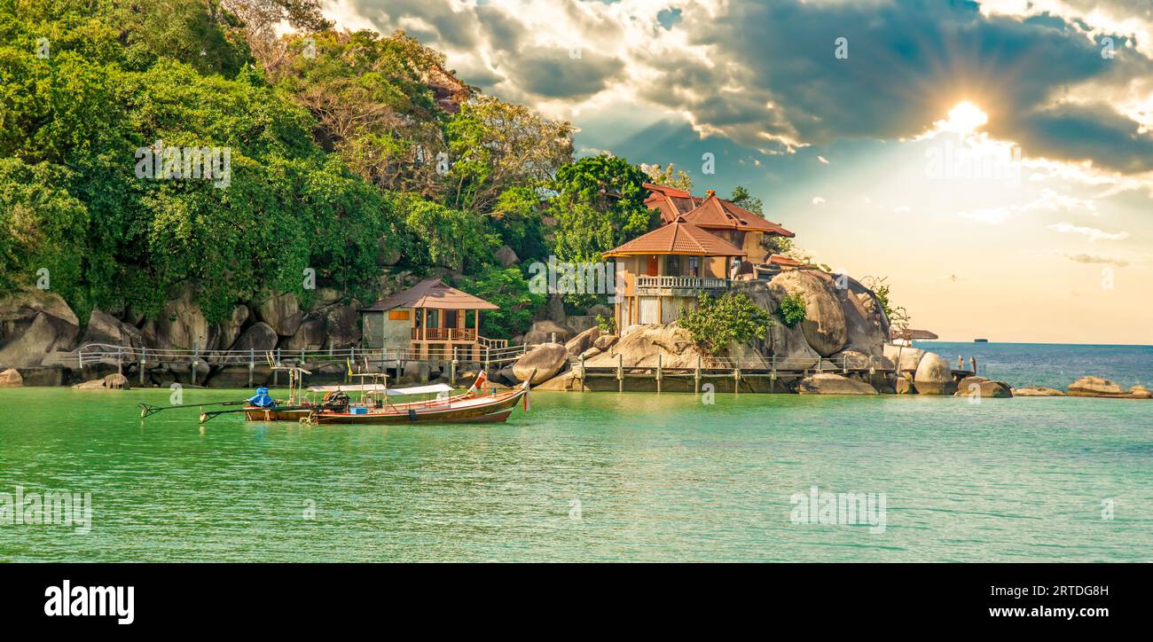 Bungalow fotografati dal traghetto sulla costa di Ko Tao, Thailandia, nascosti tra palme e rocce e posti a gradini verso l'oceano. Foto Stock