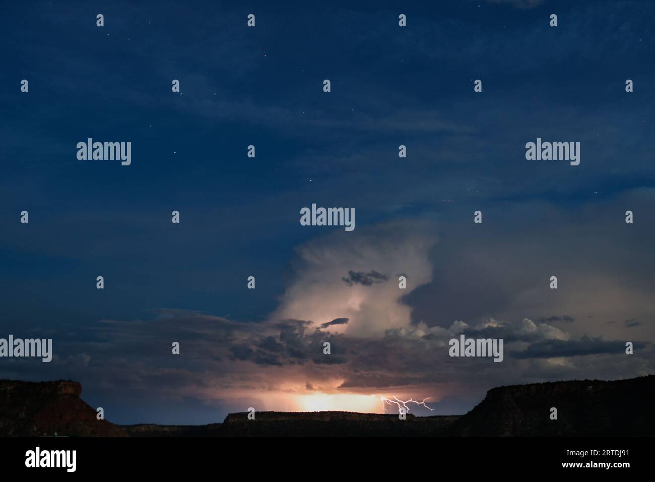 Un fulmine blu stripa su un cielo grigio inquietante, illuminando le nuvole sparse Foto Stock