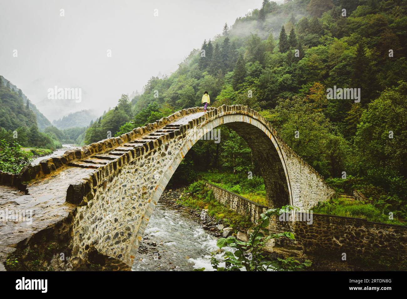 Passeggiata turistica femminile sul vecchio ponte ottomano ad Ayder , Turchia. Punti di interesse per i viaggi a Firtina Creek Foto Stock