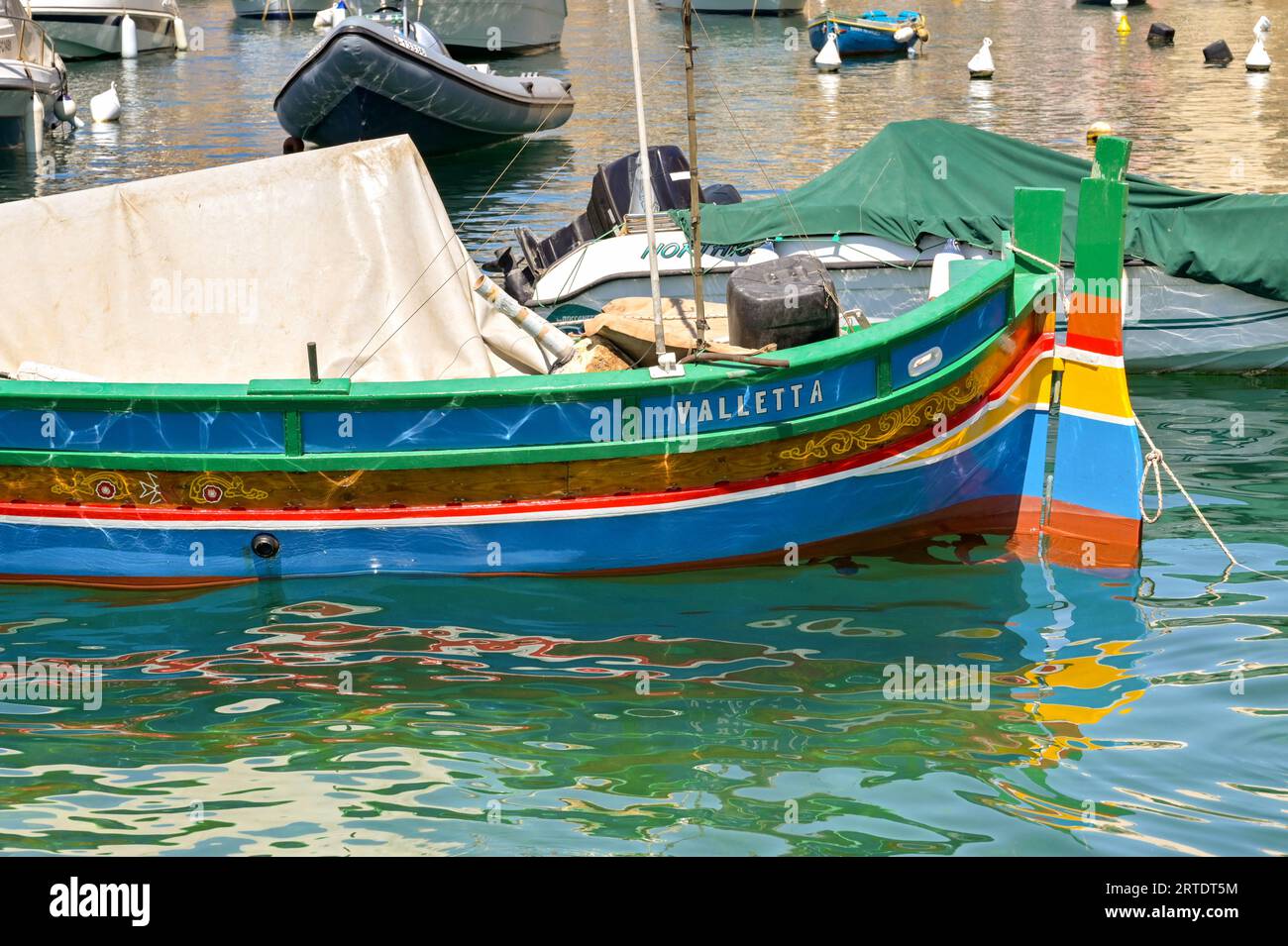 St Julians, Malta - 2 agosto 2023: Piccolo peschereccio in legno dipinto in diversi colori nel porto vicino a St Julians. Foto Stock