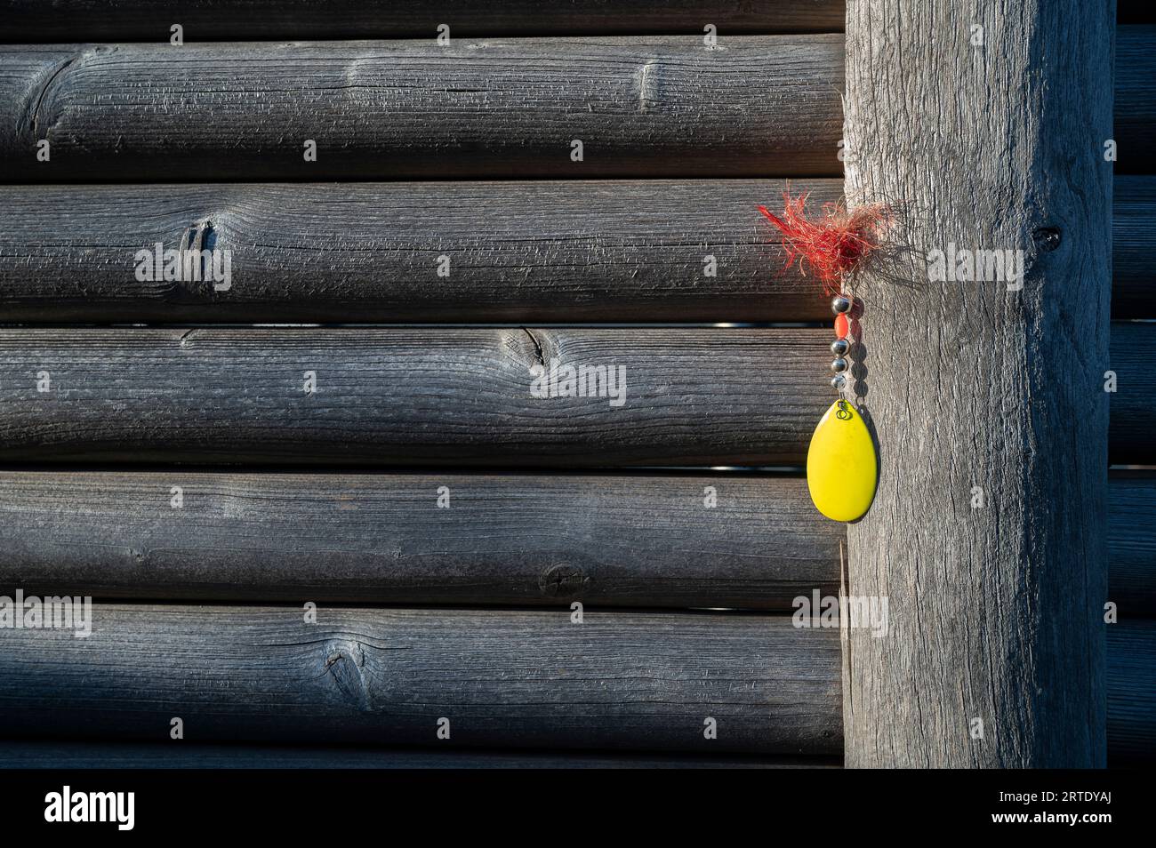 attrezzatura da pesca gialla appoggiata su una recinzione grigia con ardesia orizzontali Foto Stock