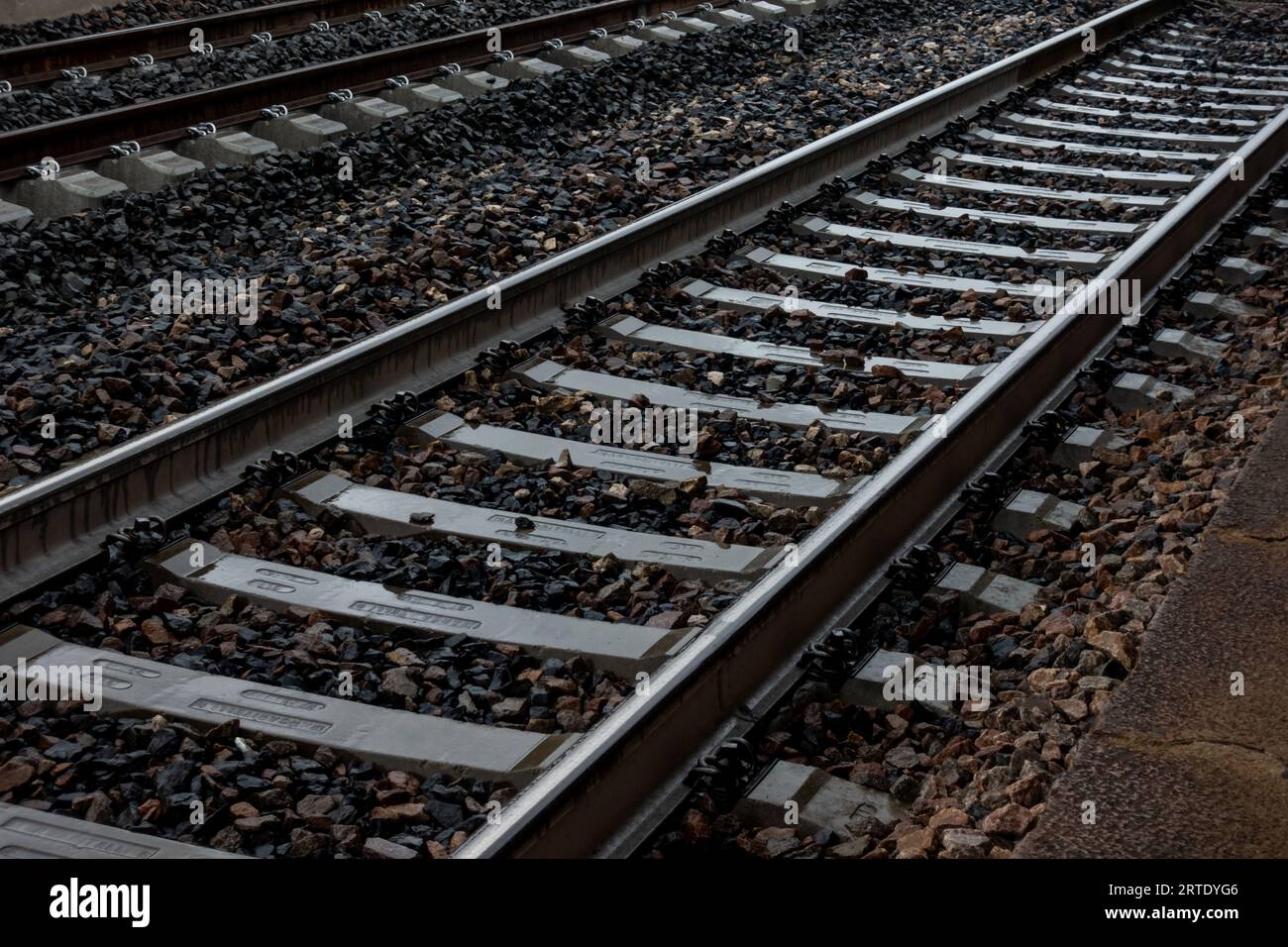 binario del treno scuro con ghiaia sotto le rotaie e i binari ferroviari Foto Stock