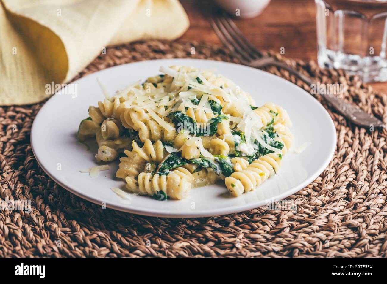 Pasta di fusilli con spinaci e ricotta guarnita con parmigiano grattugiato Formaggio su piatto bianco Foto Stock