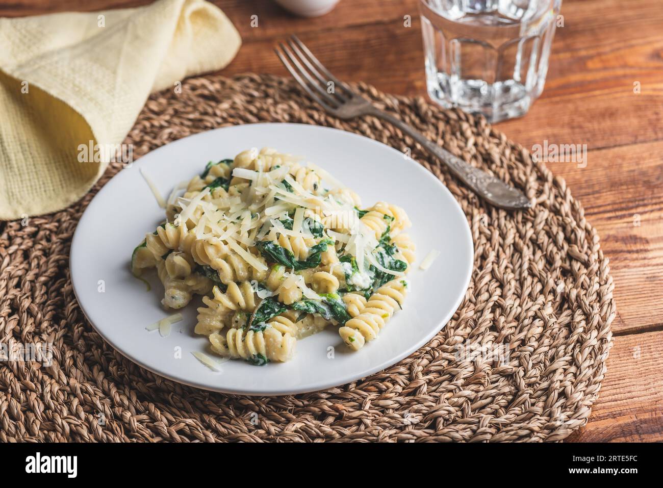 Pasta di fusilli con spinaci e ricotta guarnita con parmigiano grattugiato Formaggio su piatto bianco Foto Stock