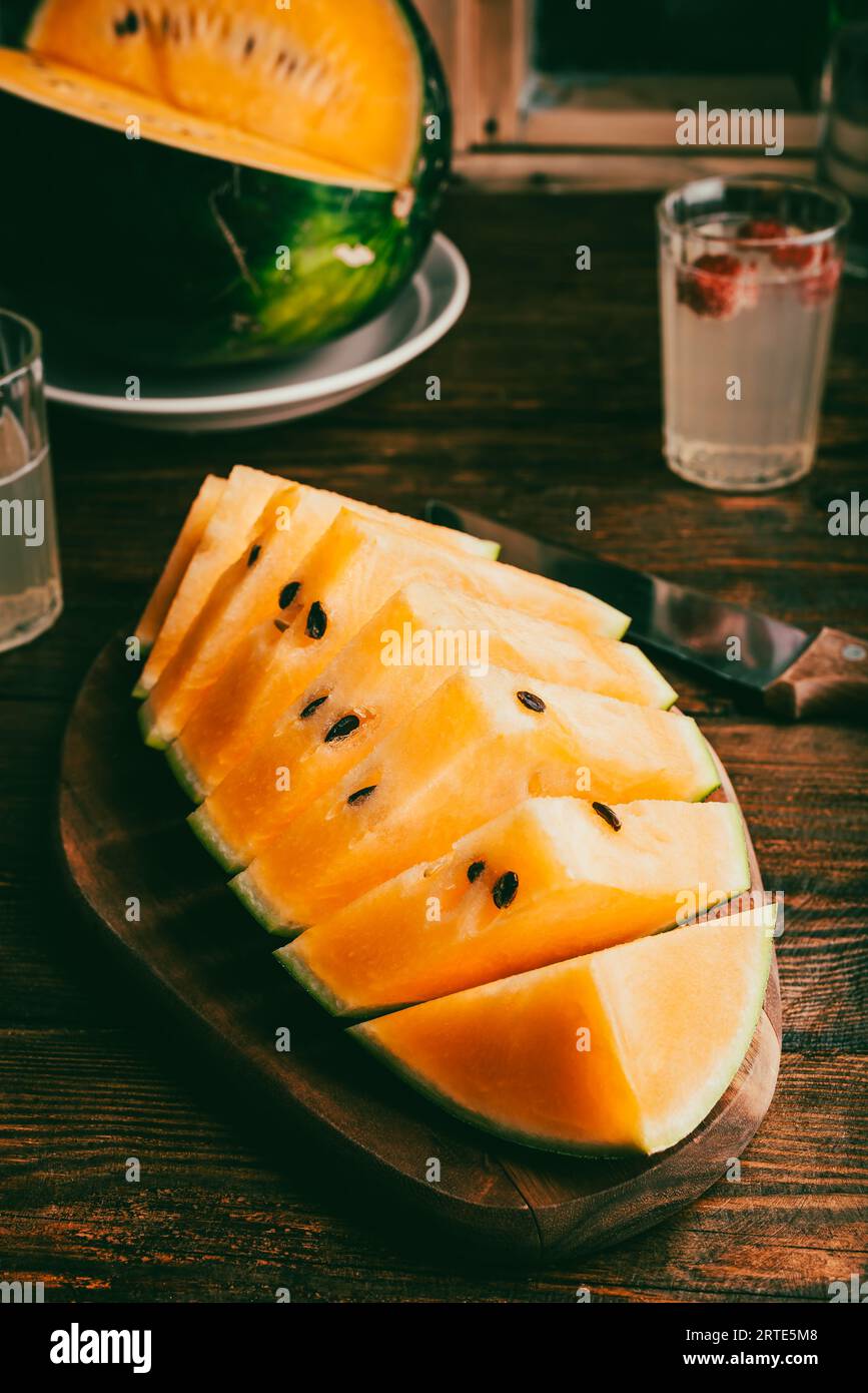 Cocomero giallo a fette su una tavola di legno Foto Stock