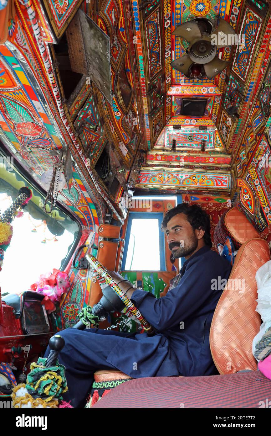 Camionista pakistano nella sua cabina decorata Foto Stock