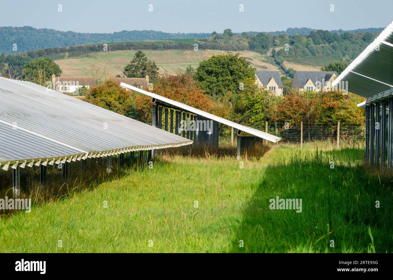 Laterale, vista dettagliata dei pannelli solari, unità di lavoro, illuminazione e riflesso della luce del sole del tardo pomeriggio, con case di campagna lontane all'orizzonte Foto Stock