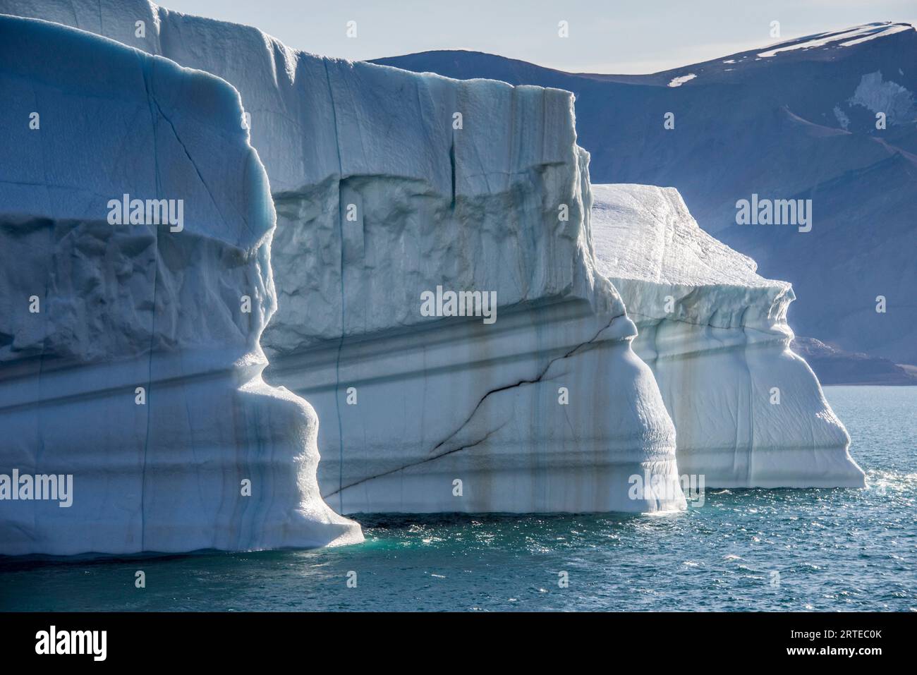 Primo piano di un grande iceberg con striature limose che galleggiano nelle acque blu ghiacciate del fiordo Kaiser Franz Joseph; Groenlandia orientale, Groenlandia Foto Stock
