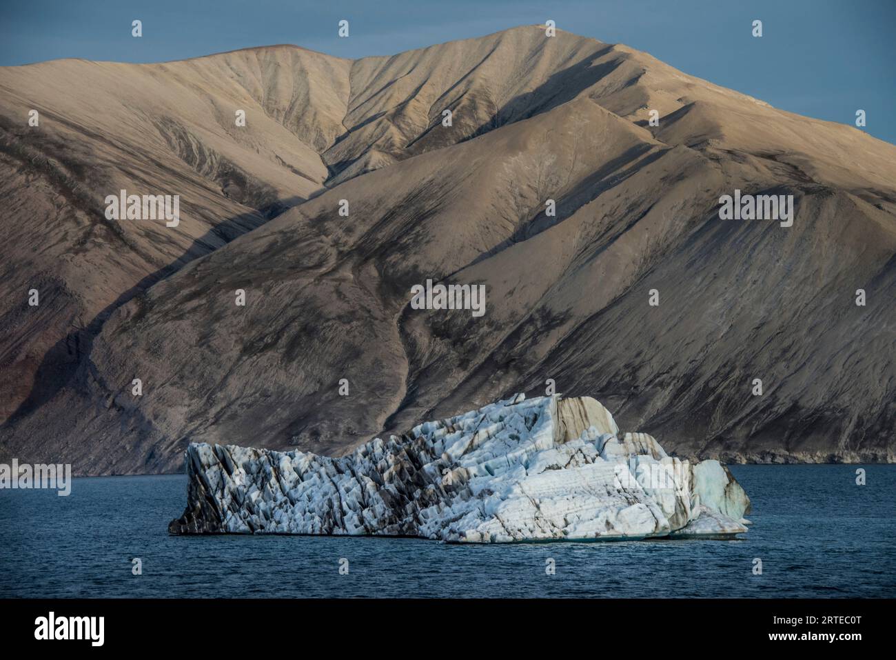 Iceberg striato di limo galleggiante nel Kaiser Franz Joseph Fjord della Groenlandia; Groenlandia orientale, Groenlandia Foto Stock