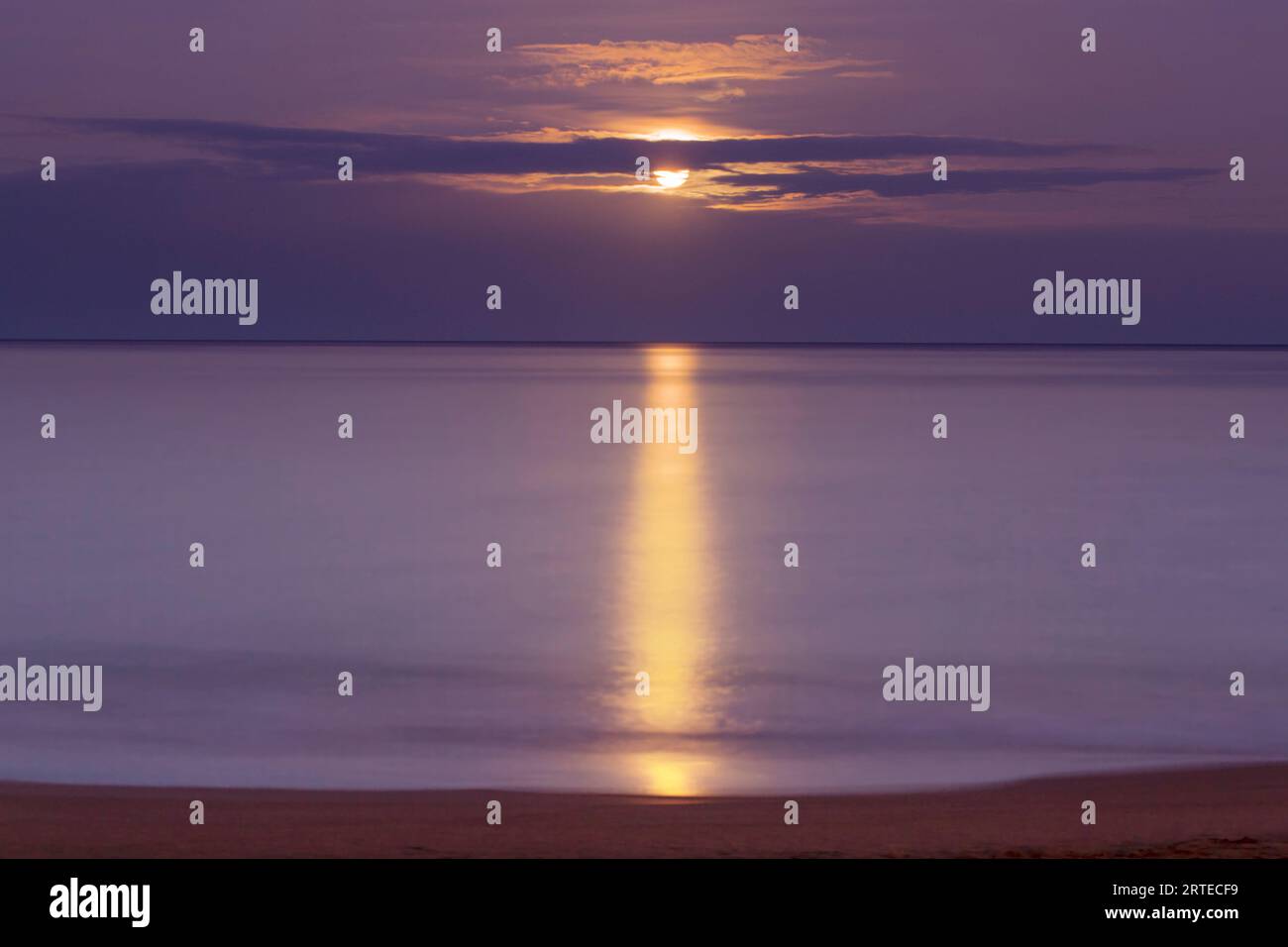 La luce dorata si riflette sull'Oceano Pacifico con l'ambientazione della luna piena al Kamaole Beach Park; Kihei, Maui, Hawaii, Stati Uniti d'America Foto Stock