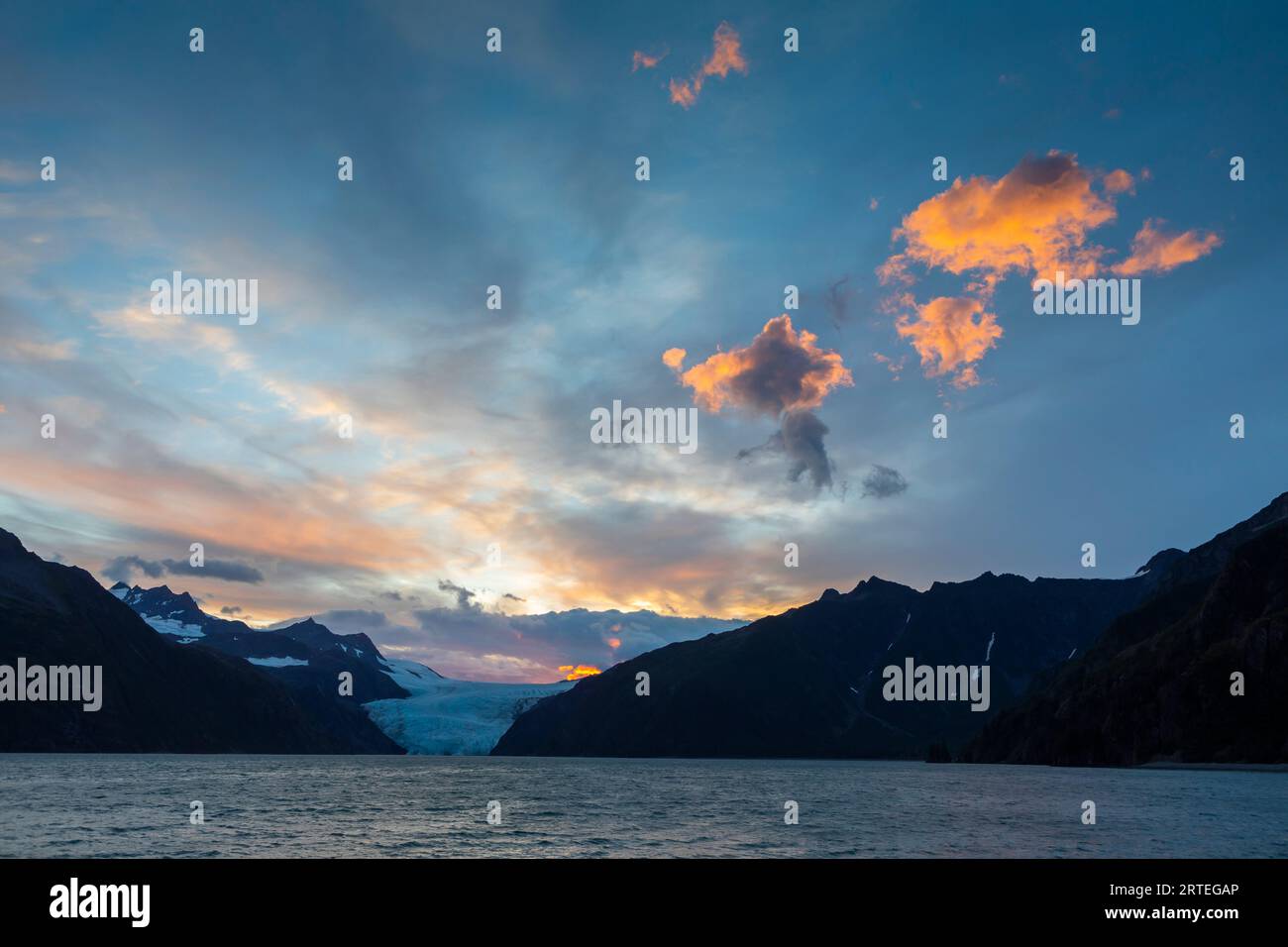 Tramonto sul ghiacciaio Holgate e sulle montagne Kenai, con nuvole accese in una giornata estiva a Holgate Arm, Aialik Bay, Kenai Fjords National Park, al... Foto Stock