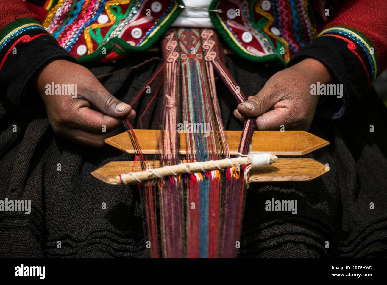 Le donne quechuan di Chinchero tessono abiti tradizionali in modi tradizionali per la vendita; Cusco, Perù Foto Stock