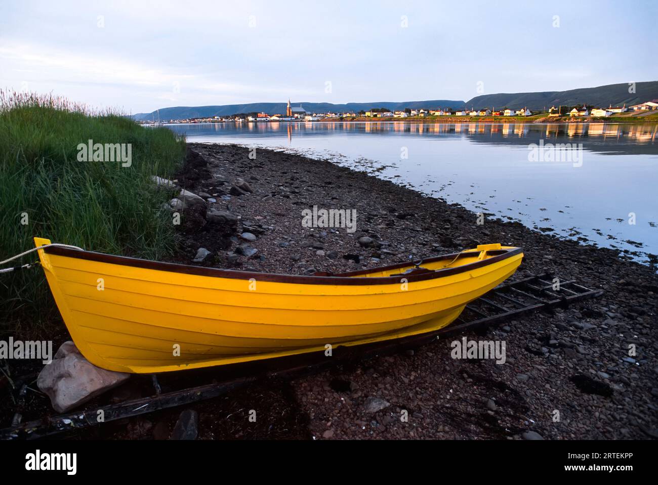 Scalata di canottaggio ormeggiata in giallo vivace sulla riva del mare vicino alla città di Cheticamp Foto Stock
