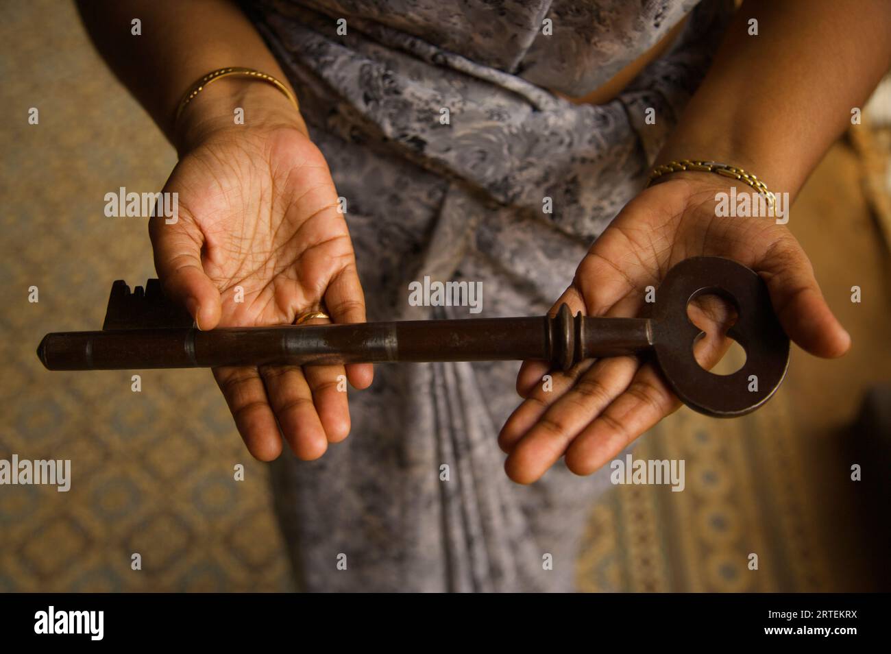 La donna tiene fuori la grande chiave di una villa; Chettinad, Tamil Nadu, India Foto Stock
