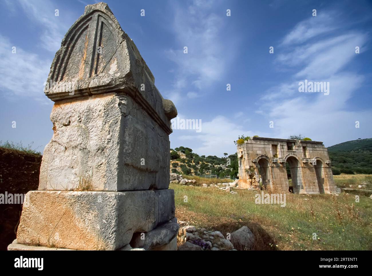 Porta romana ad arco triplo, costruita nel 100 d.C., con una struttura in pietra in primo piano; Patara, Turchia Foto Stock