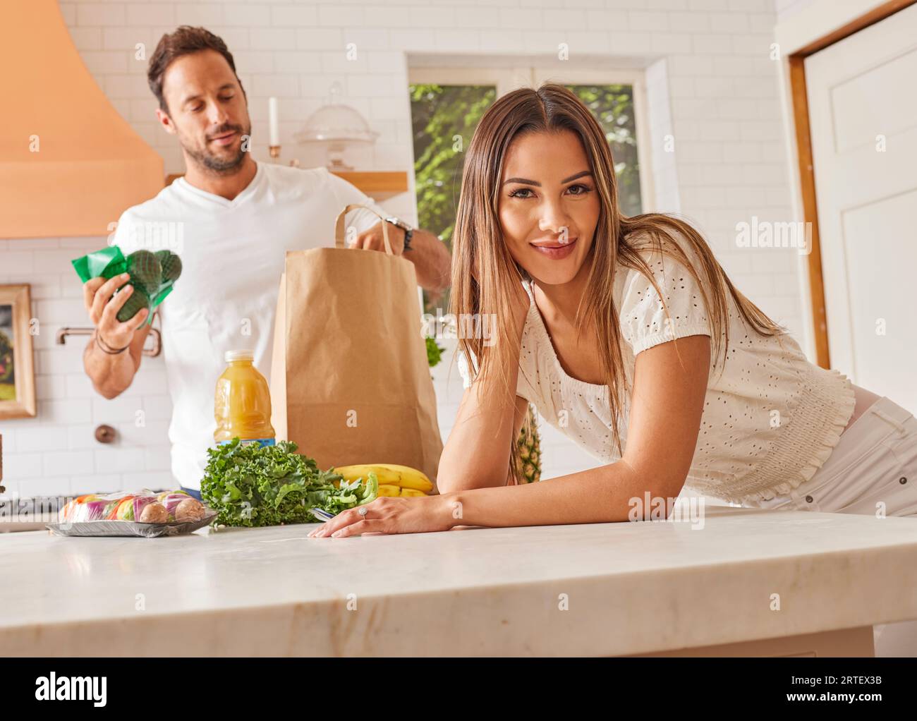 Coppia sorridente con sacchetto di carta e alimentari in cucina Foto Stock