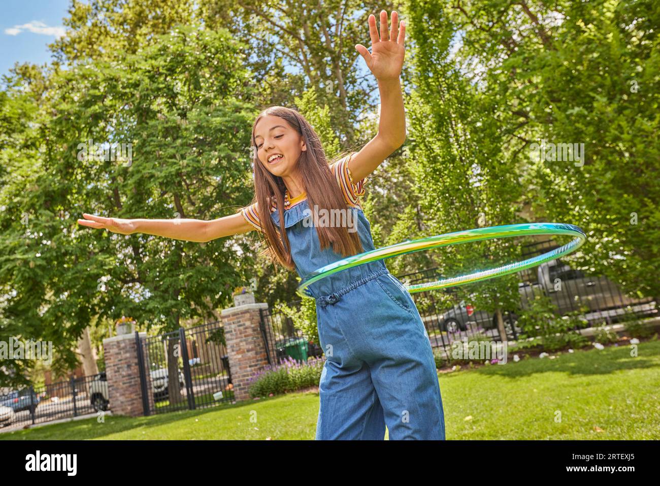 Ragazza sorridente (12-13) che gioca con hula hoop nel parco Foto Stock