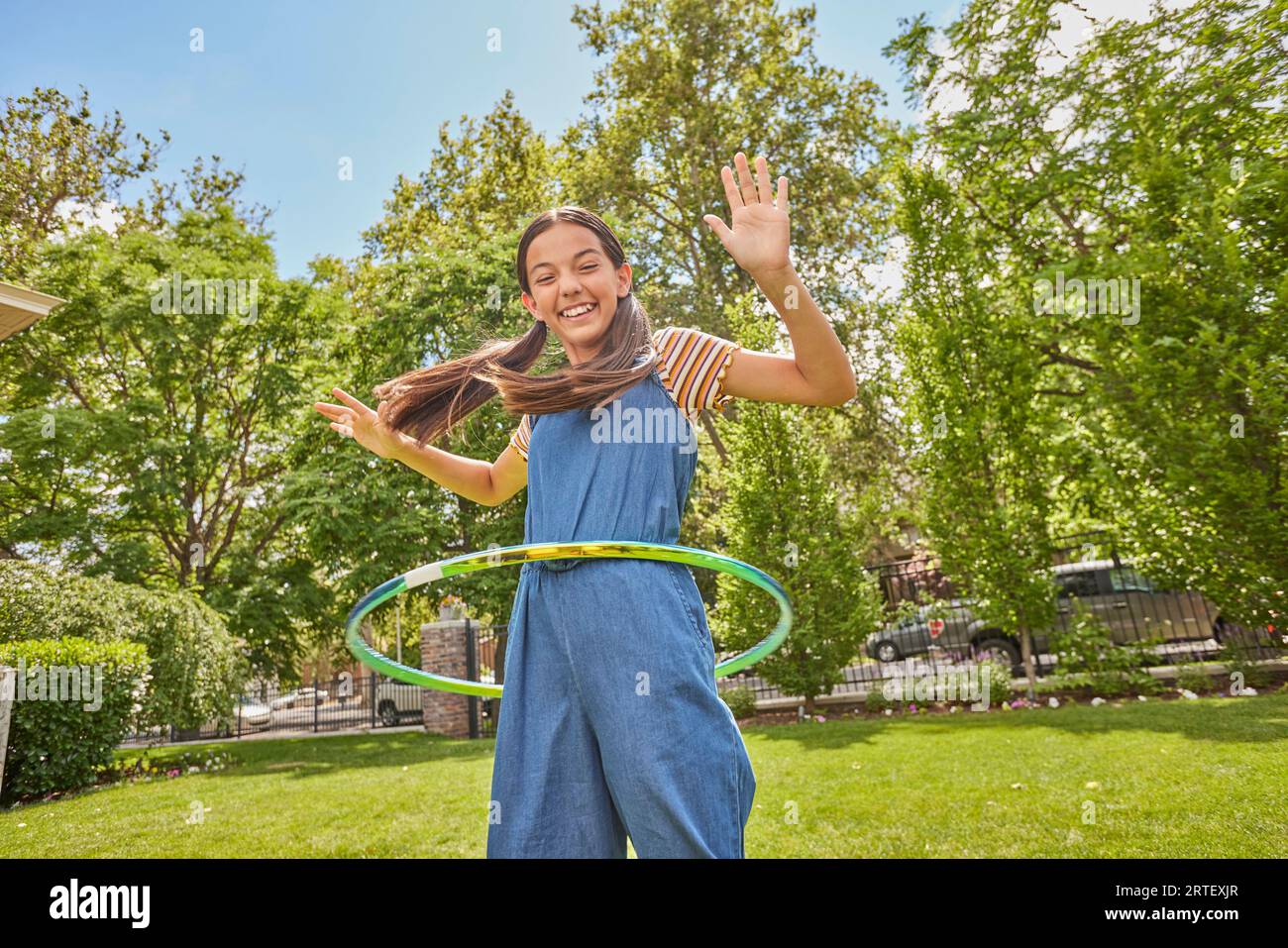 Ragazza sorridente (12-13) che gioca con hula hoop nel parco Foto Stock