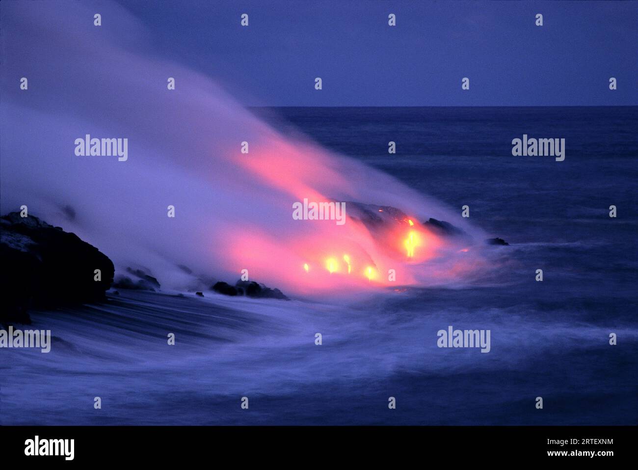 Hawaii, Big Island, Lava che entra nel mare al crepuscolo con fumo rosa brillante, arancione bagliore Foto Stock